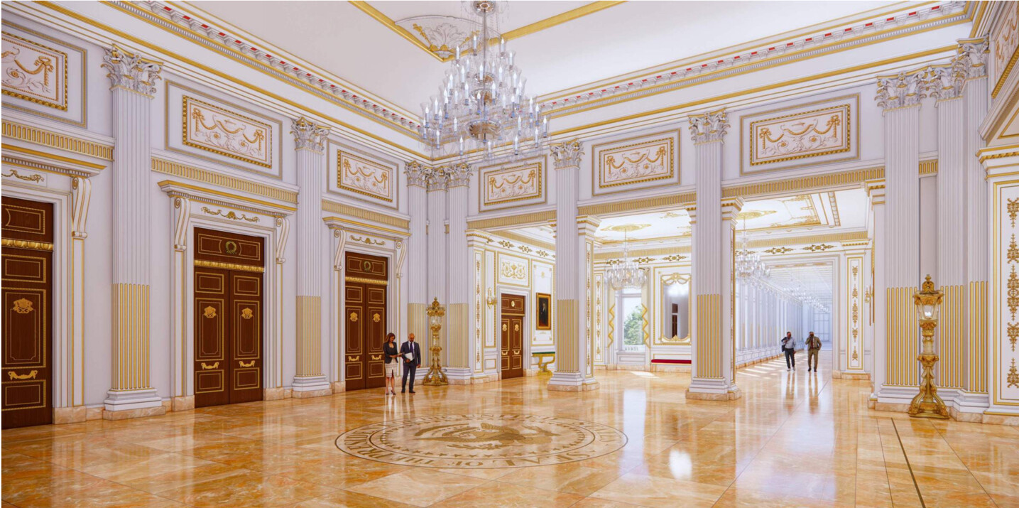 Grand, ornately decorated ballroom with gilded columns, large chandeliers, and intricate ceiling moldings. Polished marble floors feature an embossed seal at the center. People are walking and conversing within the spacious, elegant hall.